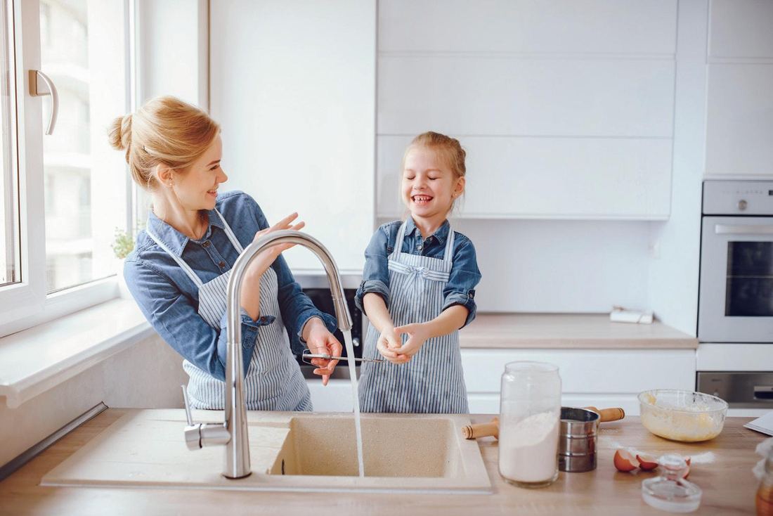A mother and daughter filling a glass at the kitchen sink